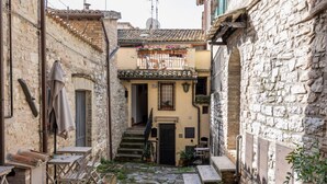 A narrow alleyway with stone buildings, a small staircase, and outdoor seating.