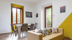 A room with a dining table, chairs, a sofa, and a window with a view. - GuestHost - Cozy apartment equipped with all comforts to accommodate 4 people, with 2 bedrooms, 2 bathrooms and private garden. Located in an elegant period building in Art Nouveau style, it is outside the restricted traffic zone, but just a 10-minute wa (Perugia)
