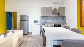 A compact kitchen with a refrigerator, microwave, and stove, a dining area with a table and chairs, and a sofa with cushions. - GuestHost - Cozy apartment equipped with all comforts to accommodate 4 people, with 2 bedrooms, 2 bathrooms and private garden. Located in an elegant period building in Art Nouveau style, it is outside the restricted traffic zone, but just a 10-minute wa (Perugia)