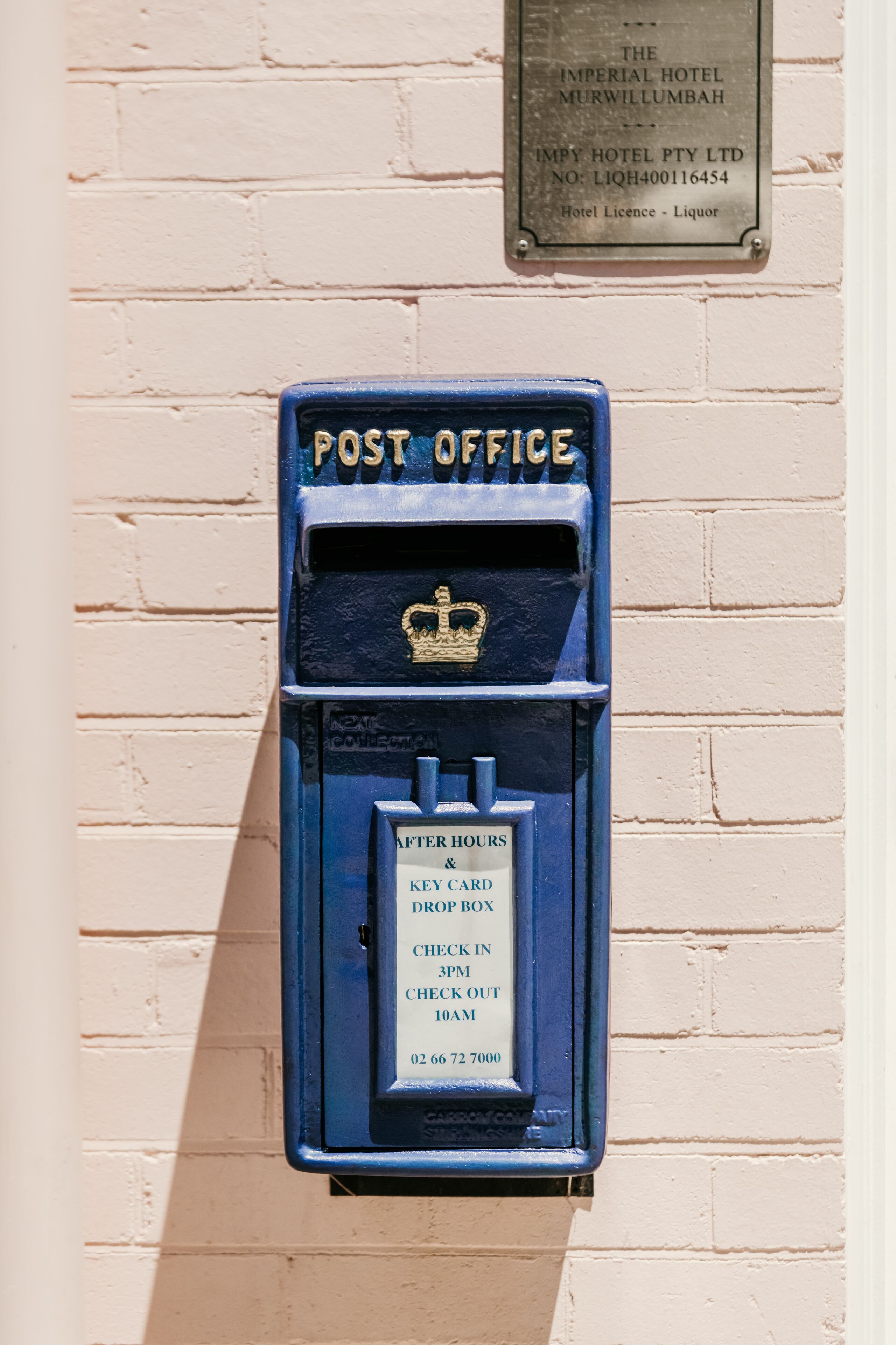 A blue post office with a plaque above it.