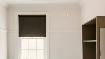 A bedroom with a bed, a ceiling fan, a window with blinds, and a wardrobe.