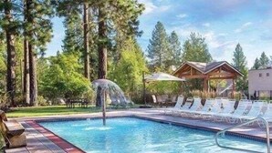 Une piscine agrémentée d’un élément décoratif aquatique, entourée de chaises longues et d’une terrasse en bois.
