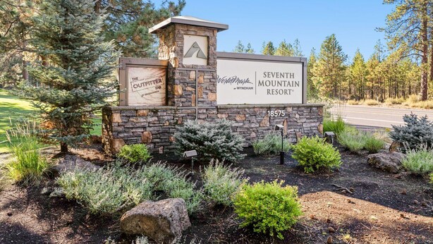 Une enseigne pour le complexe hôtelier Seventh Mountain Resort, avec un mur en pierre et un logo représentant un sommet de montagne.