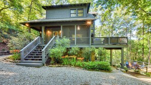 A two-story house with a covered porch, a staircase, and a deck. - 'Burton on the Rocks' Lake Retreat w/ Hot Tub! (Clayton)