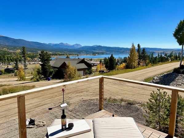 A scenic view from a balcony overlooking a lake, mountains, and a small town.