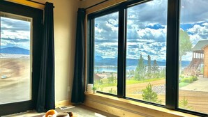 Una stanza con ampie finestre che si affaccia su un paesaggio montano e un rifugio di legno.