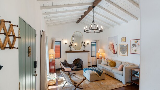 A cozy living room with a fireplace, a sofa, a rocking chair, and a chandelier. - Spanish Style Highland Park Home + Free Parking (Los Angeles)