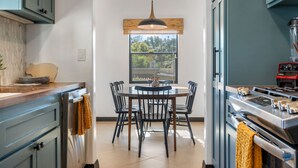 A modern kitchen with a round dining table, black chairs, and a hanging pendant light. - Spanish Style Highland Park Home + Free Parking (Los Angeles)