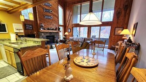 Un interior de madera con una mesa de comedor, sillas, una chimenea y una zona de cocina.