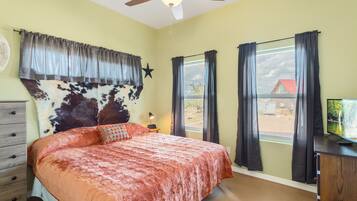 A bedroom with a large bed, a ceiling fan, a window with curtains, and a star decoration on the wall.