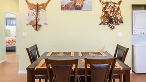 A dining area with a table set for four, flanked by two wooden chairs. Above the table, there are three mounted animal hides on the wall. - Experience the Wild West in Style: Unforgettable Getaway in Tombstone, Arizona!! (Tombstone)