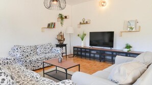 Una sala de estar con sofá, mesa de centro, televisor y estanterías decoradas.