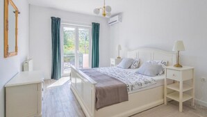 Un dormitorio con cama, mesitas de noche, cómoda y ventana con cortinas.