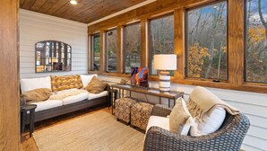 A cozy living room with a sofa, ottomans, and a wicker chair. - Mountain Home in Private Gated Community (Boone)
