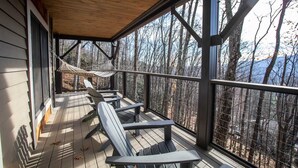 A wooden deck with Adirondack chairs and a hammock overlooking a forested area. - Mountain Home in Private Gated Community (Boone)