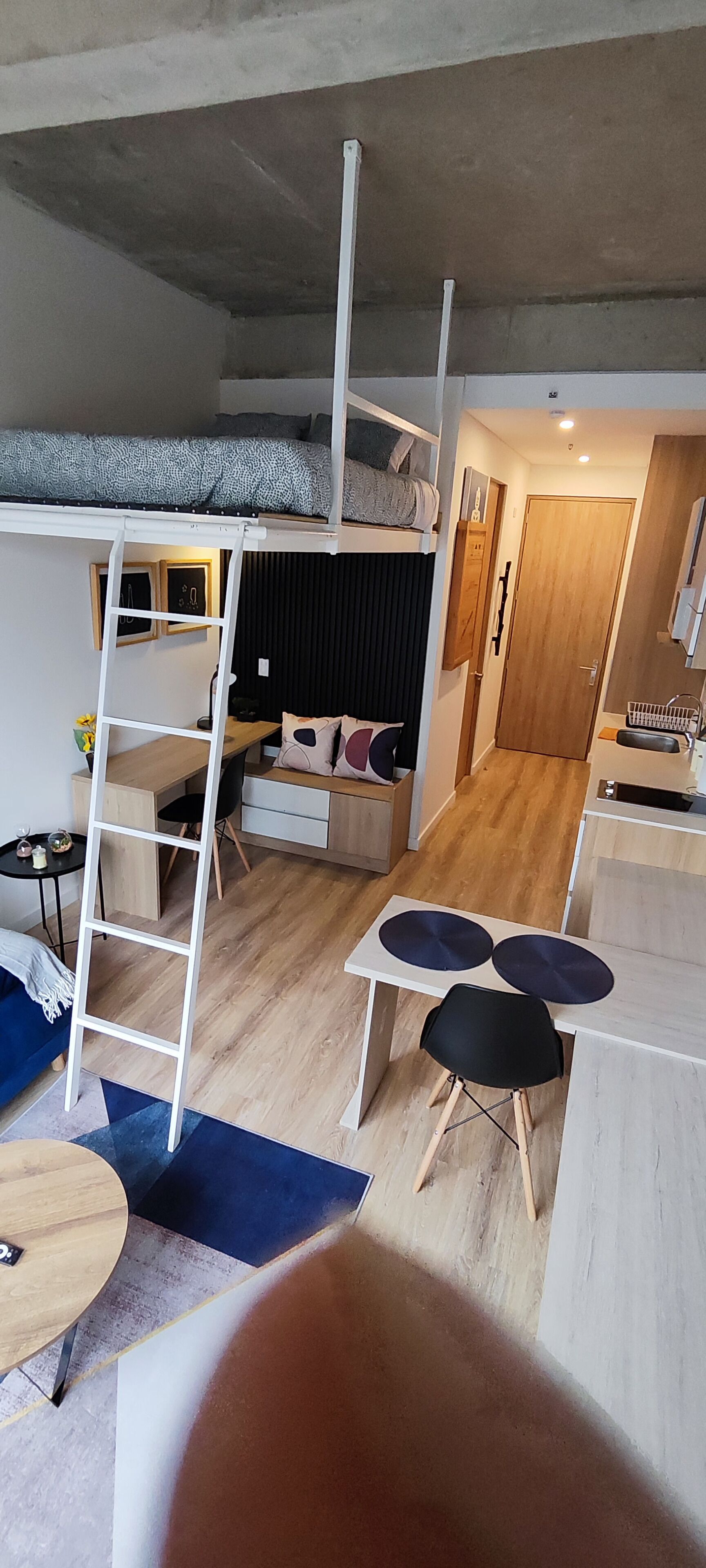 Un dormitorio tipo loft con literas, un escritorio, una silla y una mesita.