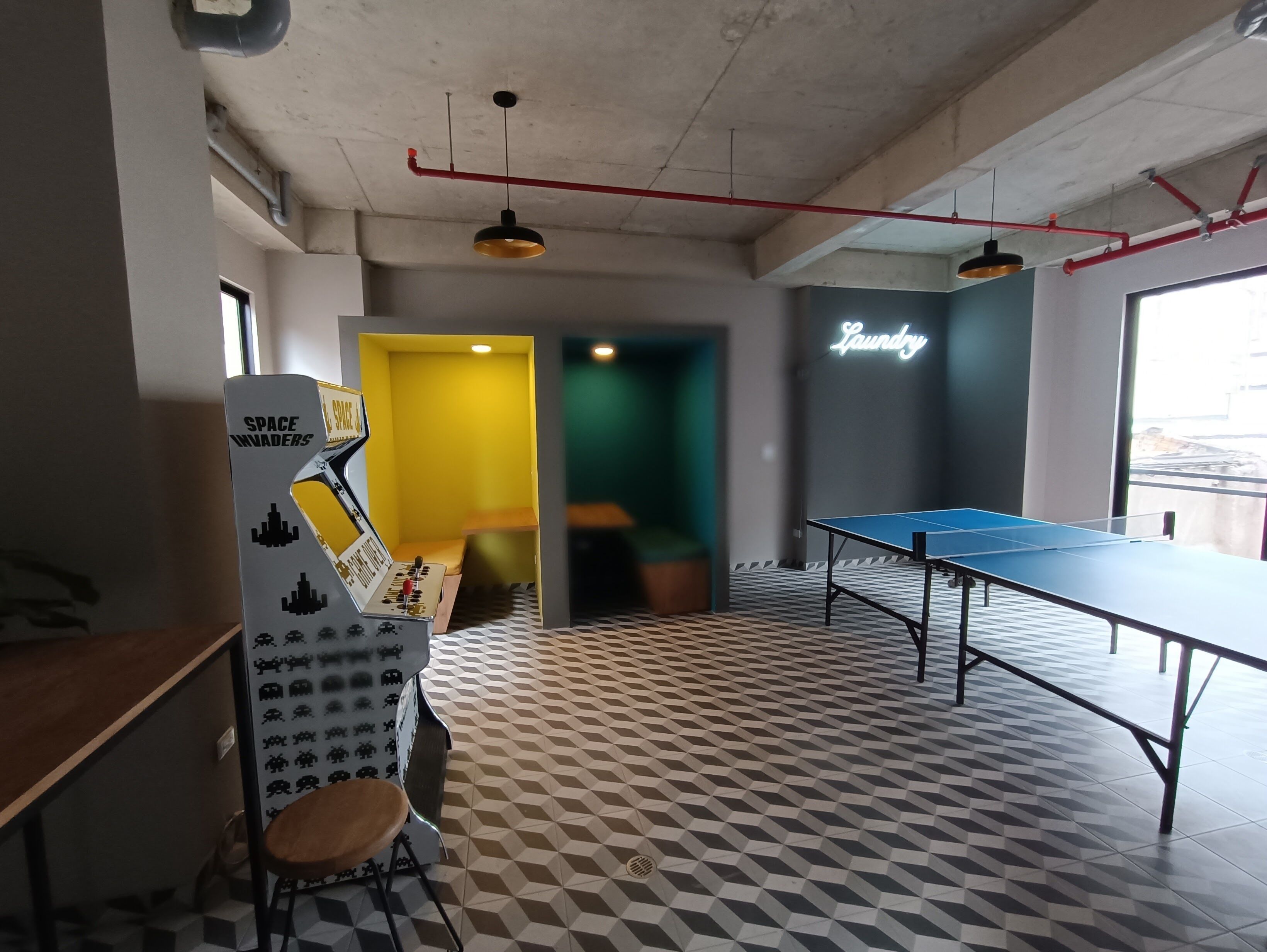 Una habitación con mesa de ping pong, decoración de pared con temática espacial y un letrero de neón que dice 'Laundry'.