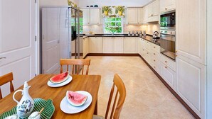 Une cuisine moderne avec des meubles blancs, une table à manger en bois et un réfrigérateur.
