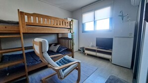 A dormitory room with bunk beds, a desk, a TV, and a window. - Yolo House (Incheon)