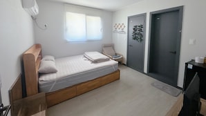 A small, single-bed room with a wooden bed frame, a bedside table, a chair, a wardrobe, and a window. - Yolo House (Incheon)