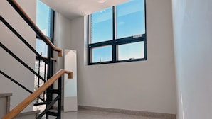 A staircase with a handrail and a window with a view of the sky. - Yolo House (Incheon)