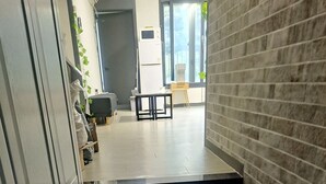 A modern kitchen with grey tiles, a wooden cabinet, and a small table with chairs. - Yolo House (Incheon)