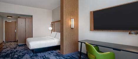 Habitación de hotel con una cama, un escritorio, una silla verde, un panel decorativo de madera y un espejo grande.