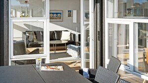 A modern interior with a dining area, a sofa, and a glass door leading to an outdoor space.