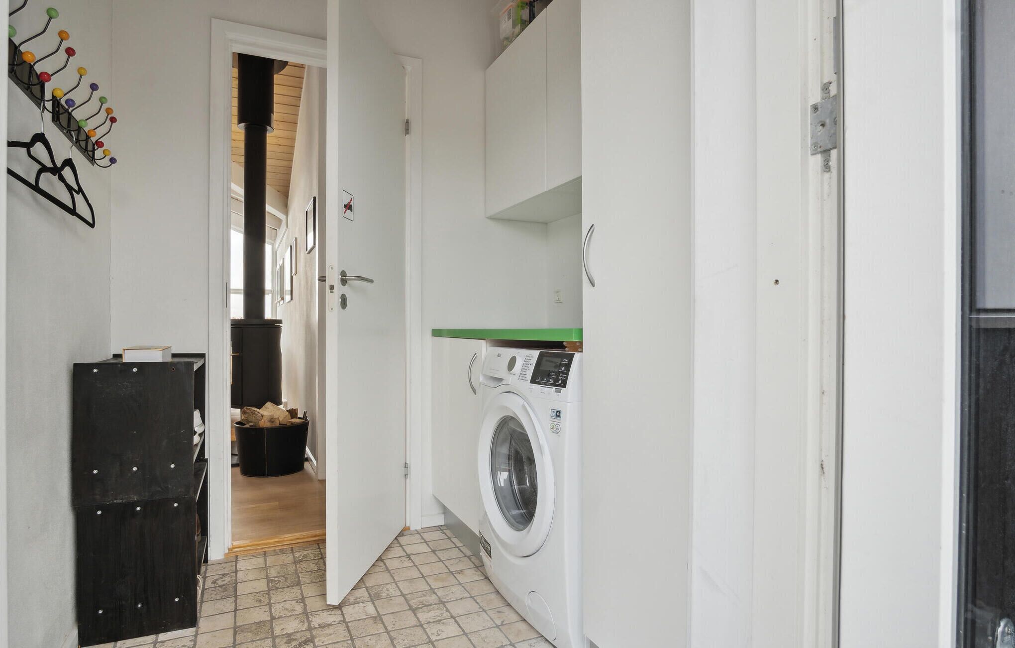 A laundry room with a washing machine, a drying rack, and a wood-burning stove.