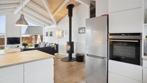 Una cocina moderna con estufa integrada, un refrigerador grande y un comedor con sofá y mesa.