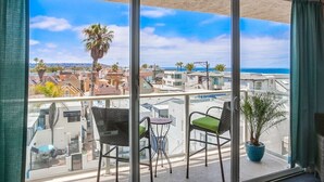 Ein Balkon mit Blick auf eine Küstenstadtlandschaft, mit einer Palme und einem Blumentopf.