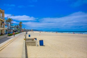 Una playa con orilla arenosa, un pasillo de madera y edificios a lo largo de la costa.