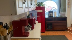 Une cuisine de taille réduite avec des meubles blancs, un réfrigérateur rouge et un plan de travail en bois.