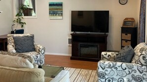 Un salon avec deux canapés, un téléviseur et une cheminée.