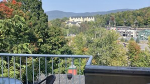 Ein Balkon mit Tisch und Stühlen, mit Blick auf ein großes Gebäude mit zahlreichen Fenstern und einem Parkplatz.