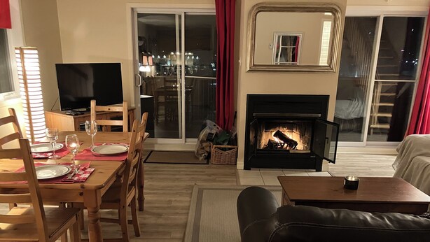 Ein Wohnzimmer mit Kamin, einer Essecke mit Tisch für zwei Personen und einem Sofa.