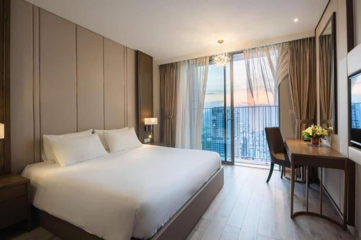 A hotel room with a large bed, a desk, and a view of the city.