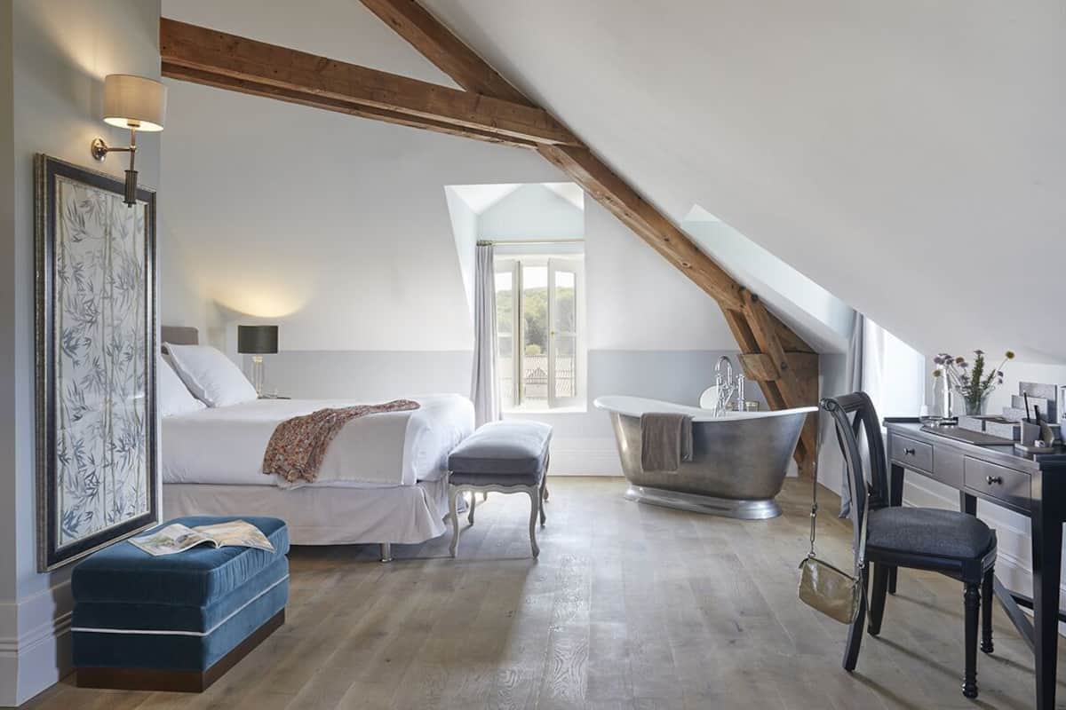 Ein Schlafzimmer mit Bett, Schreibtisch, Stuhl, Badewanne und Fenster.