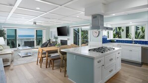 Et moderne køkken med en stor ø, et spiseområde med udsigt og en opholdsstue med fjernsyn og siddepladser.