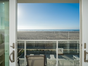 A balcony with a view of a pebble beach and the ocean.