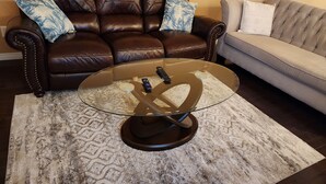Un salon avec une table basse en verre, deux canapés et des tapis à motifs.