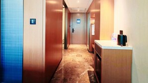 A hotel hallway with a marble floor, wooden walls, and a reception desk with a coffee machine. - Hampton by Hilton Dongguan Cntrl Square (Dongguan)
