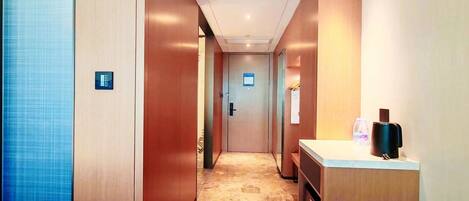 A hotel hallway with a marble floor, wooden walls, and a reception desk with a coffee machine.