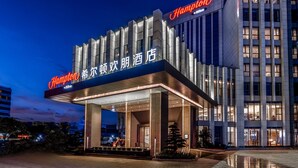 A modern hotel with a prominent 'Hampton' sign, featuring a sleek facade and illuminated entrance. - Hampton by Hilton Dongguan Cntrl Square (Dongguan)