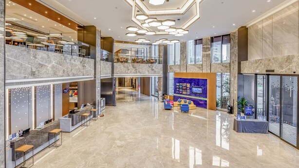 A spacious lobby with a marble reception desk, seating areas, and a modern ceiling design. - Hampton by Hilton Dongguan Cntrl Square (Dongguan)