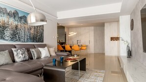 Un salon moderne avec un canapé, une table basse et un coin repas doté de chaises orange.
