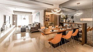 Un espace de salle à manger moderne avec une table en bois, des chaises orange et des luminaires suspendus.