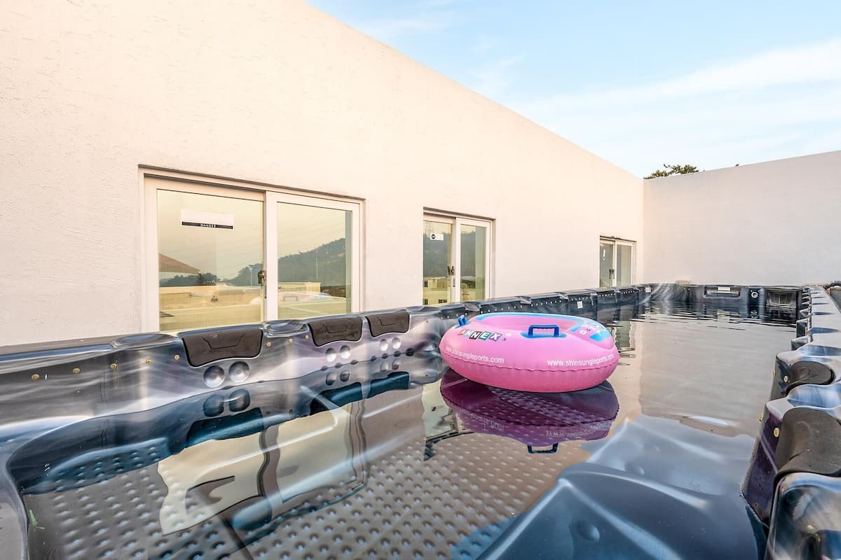 A hot tub area with a pink inflatable ring, a glass door, and a view of the surrounding landscape.