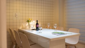 Una mesa de comedor con sillas, una botella de vino y dos copas.