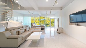 Una sala moderna con sofá, cama, televisión y escalera.